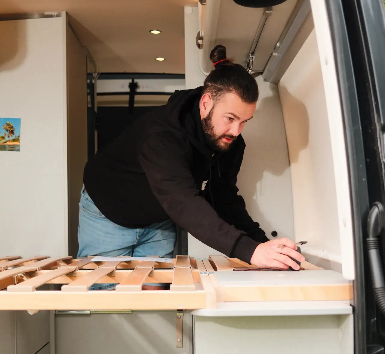 Mann misst sein Bett im Camper aus