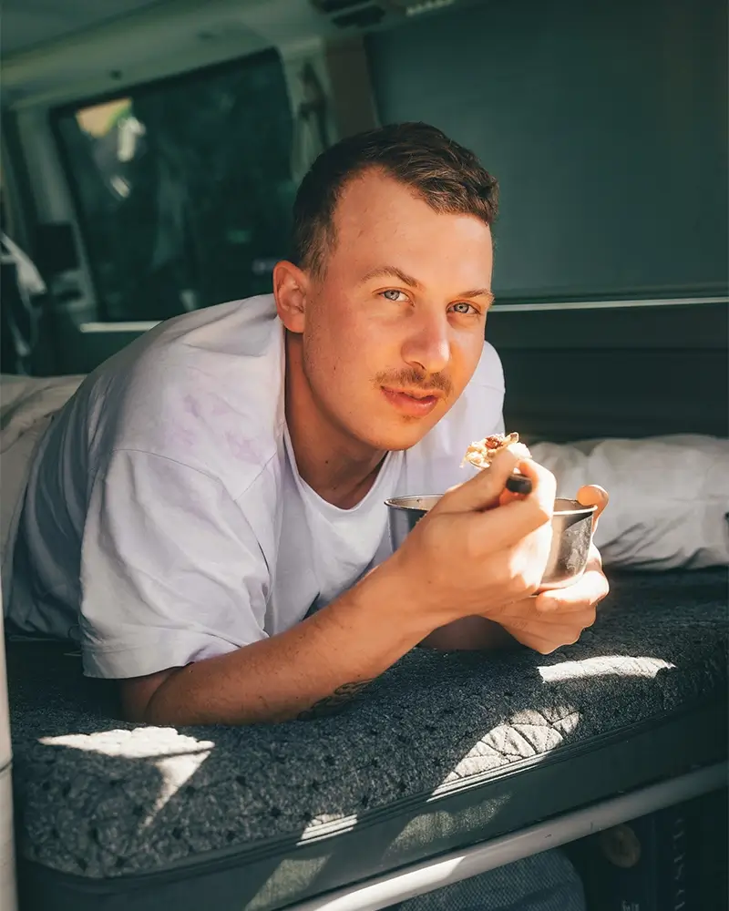 Mann isst Muesli auf einer Vanmade Matratze