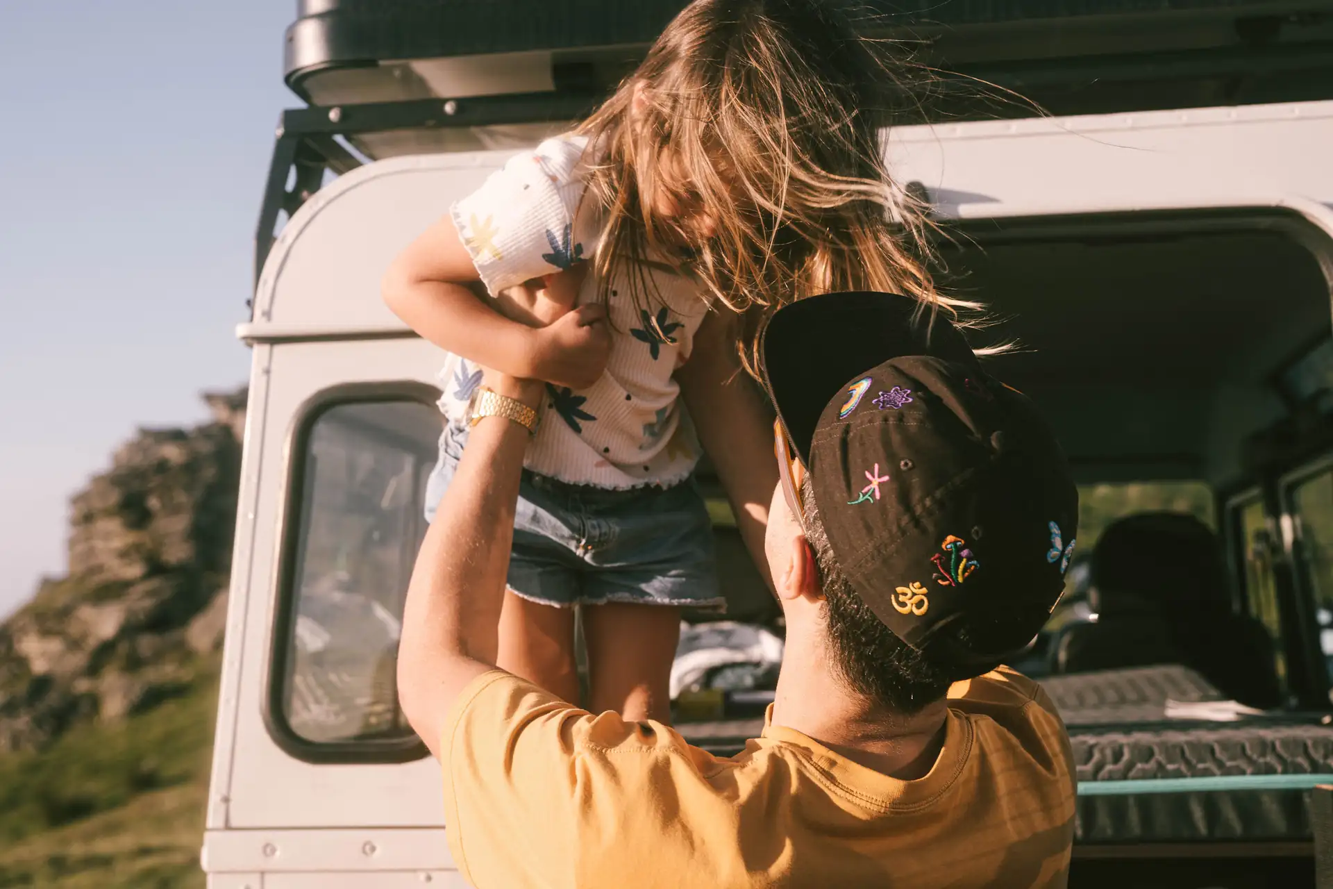 Lifestye, Vater haelt sein Kind hoch, vor Fahrzeug, Morgenstimmung